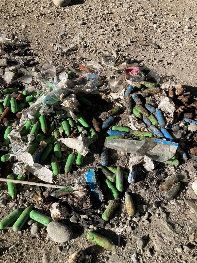 This photo shows a burn pile of metal nitrous oxide canisters, also known as chargers or whippets.