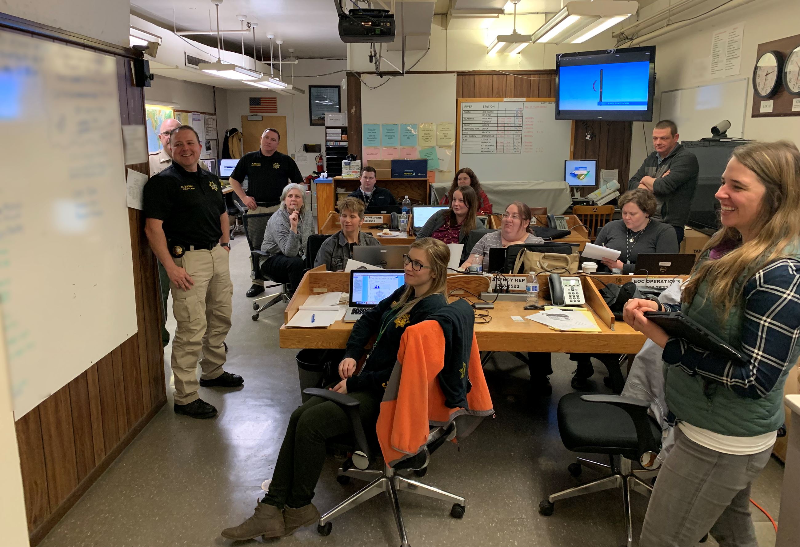 Small room filled with emergency response workers reviewing a whiteboard