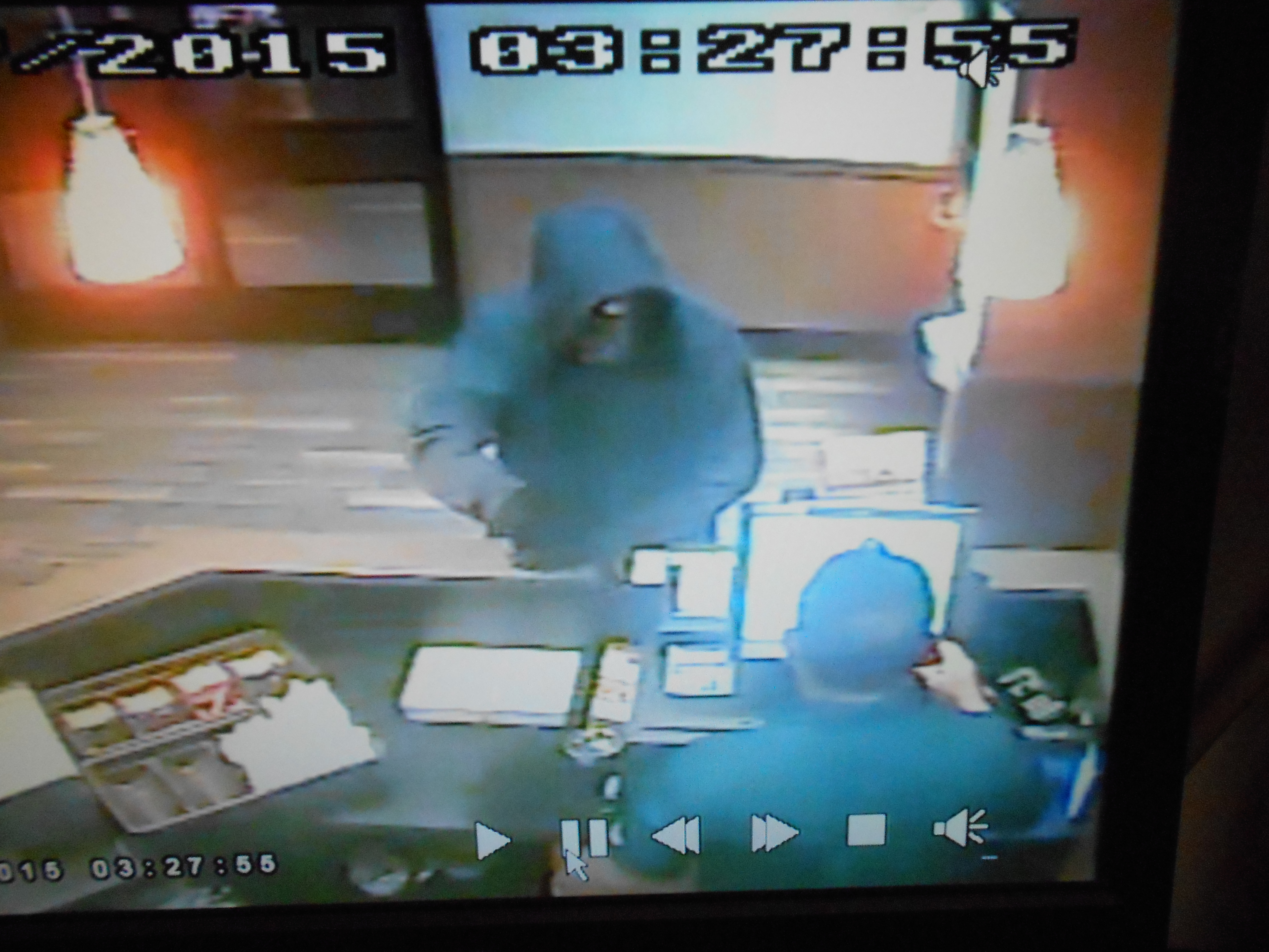 man wearing a dark hooded sweatshirt with a camouflage mask brandishing a gun 